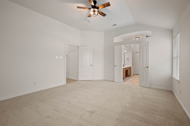 unfurnished bedroom featuring connected bathroom, light colored carpet, vaulted ceiling, visible vents, and baseboards
