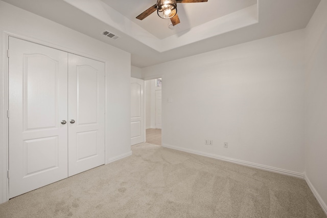 unfurnished bedroom featuring a closet, visible vents, carpet flooring, a raised ceiling, and baseboards