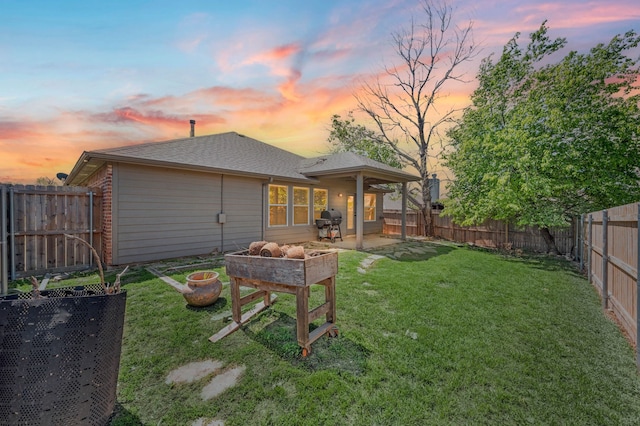 back of house with an outdoor fire pit, a fenced backyard, a lawn, and roof with shingles