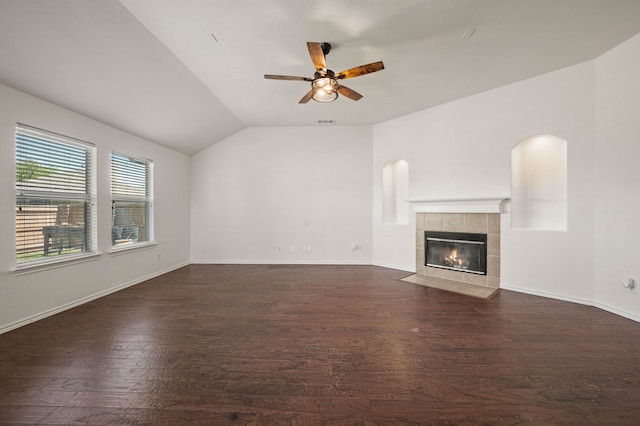 unfurnished living room featuring visible vents, a tiled fireplace, dark wood-style flooring, a ceiling fan, and vaulted ceiling