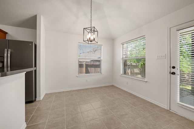 unfurnished dining area featuring lofted ceiling, an inviting chandelier, baseboards, and a healthy amount of sunlight