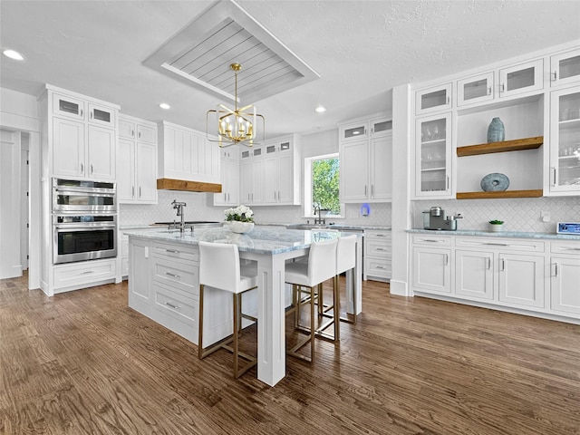 kitchen with recessed lighting, white cabinets, stainless steel double oven, and a chandelier