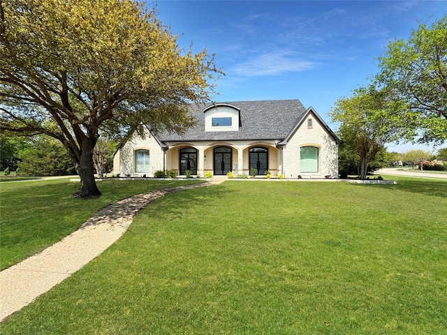 french country style house featuring french doors, roof with shingles, brick siding, and a front yard
