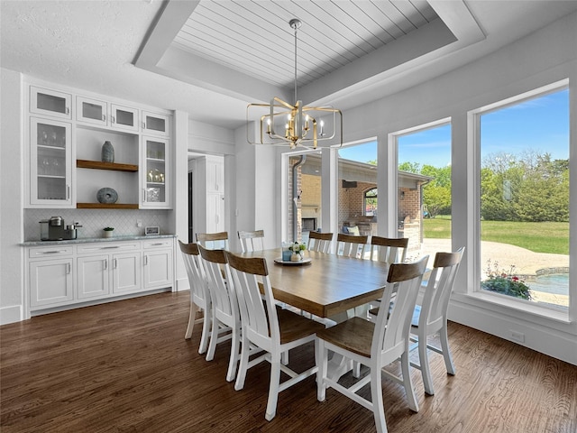 dining room featuring dark wood-style flooring, a tray ceiling, and an inviting chandelier