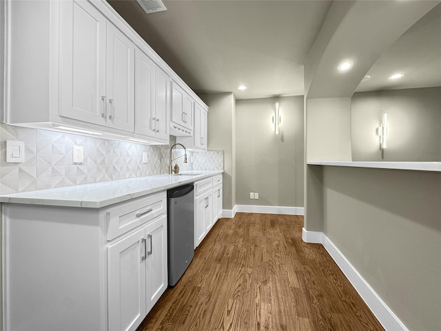 kitchen featuring decorative backsplash, dark wood-style flooring, dishwasher, a sink, and white cabinetry