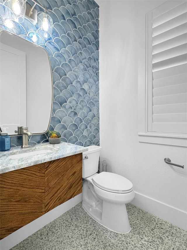half bath featuring vanity, baseboards, tile patterned floors, and toilet