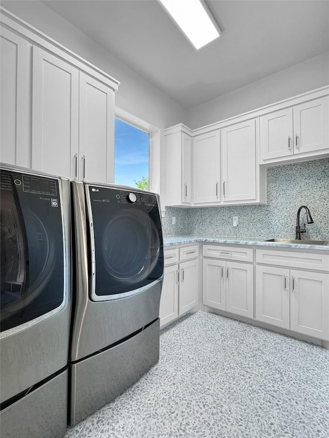 washroom with a sink, cabinet space, and washer and clothes dryer