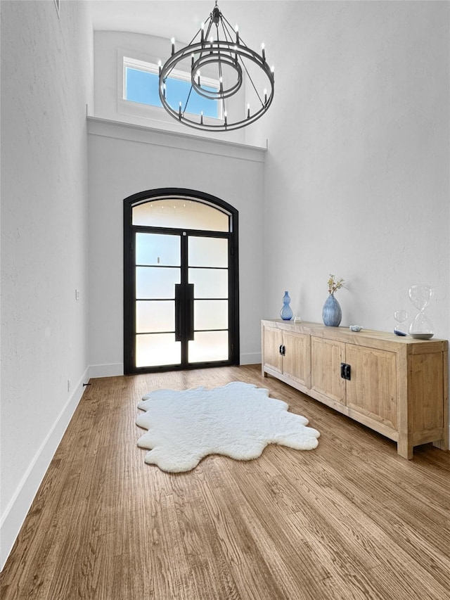 foyer entrance featuring french doors, baseboards, an inviting chandelier, and wood finished floors