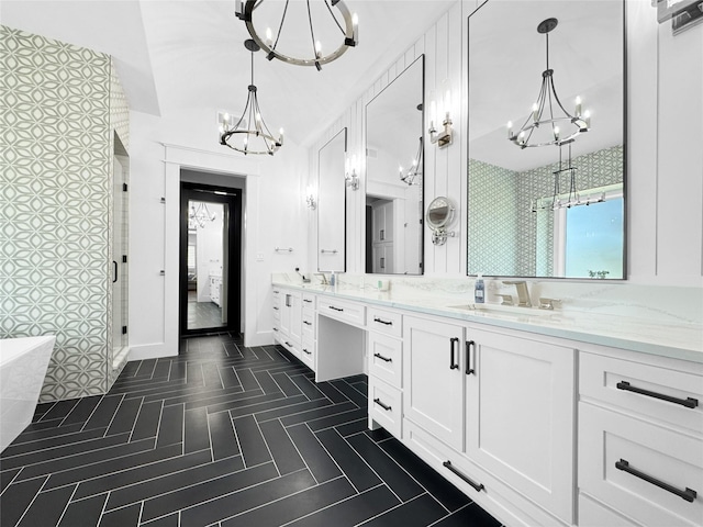 bathroom with double vanity, a freestanding bath, a chandelier, a shower stall, and a sink