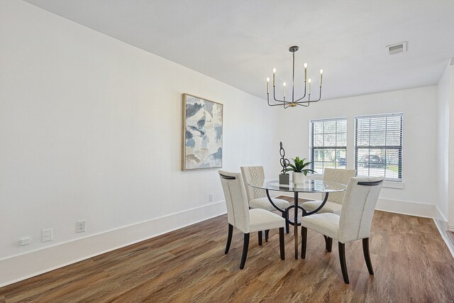 dining space featuring dark wood-style flooring, visible vents, baseboards, and a notable chandelier