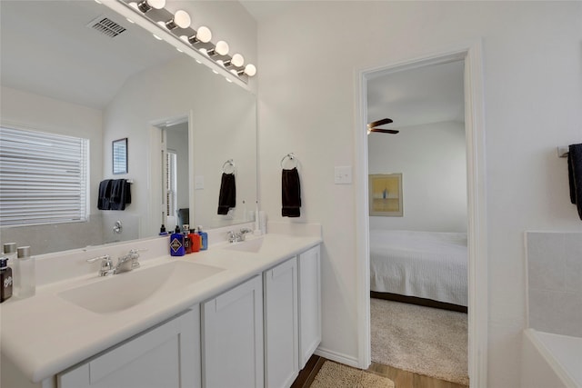 full bathroom featuring ensuite bath, visible vents, a sink, and wood finished floors