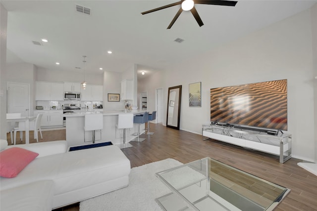 living area with light wood-style flooring, baseboards, a ceiling fan, and visible vents