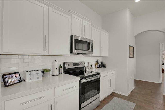 kitchen with tasteful backsplash, baseboards, arched walkways, and stainless steel appliances