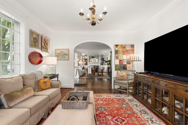 living room with crown molding, arched walkways, an inviting chandelier, and wood finished floors