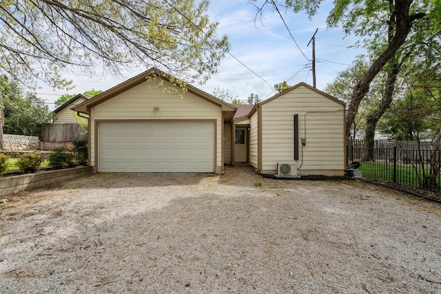 garage featuring dirt driveway, fence, and ac unit