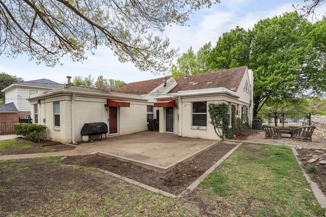 rear view of house with a patio area, fence, and brick siding