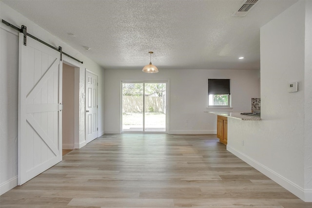 436 Nathan St, Burleson, TX 76028 - unfurnished living room with a barn door, baseboards, light wood finished floors, a textured ceiling, and recessed lighting