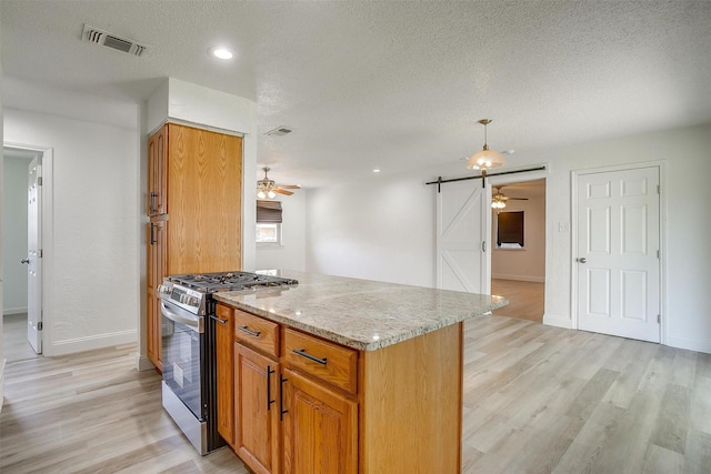 436 Nathan St, Burleson, TX 76028 - kitchen featuring a barn door, stainless steel gas range oven, a ceiling fan, light wood-style floors, and a textured ceiling
