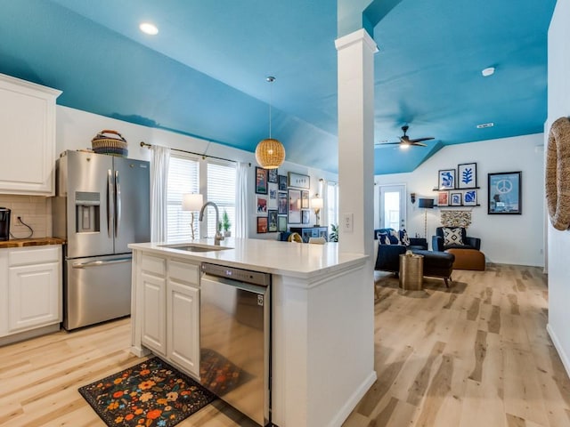 kitchen with appliances with stainless steel finishes, light wood-type flooring, open floor plan, lofted ceiling, and a sink