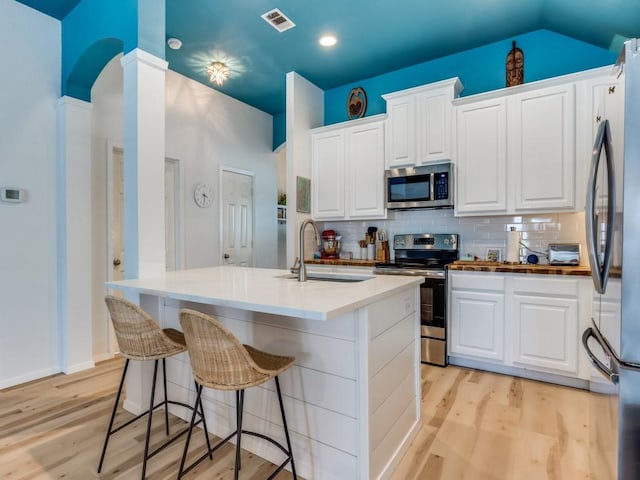 kitchen featuring light wood-style flooring, a sink, visible vents, and stainless steel appliances