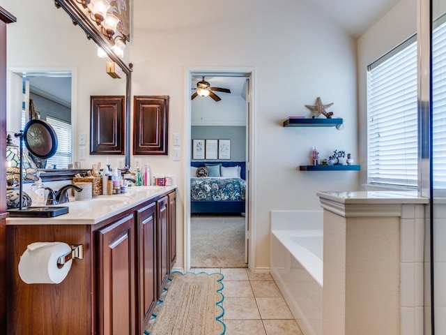 ensuite bathroom featuring a sink, ceiling fan, a garden tub, and a healthy amount of sunlight