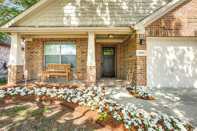 property entrance with brick siding, driveway, a porch, and a garage