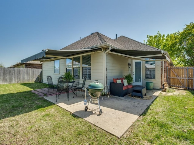 rear view of property with a shingled roof, fence private yard, a patio, and a lawn