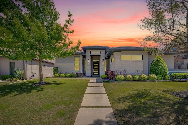 view of front of home with a garage, a front yard, and brick siding