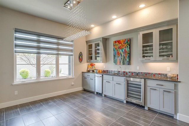 bar with baseboards, a sink, wet bar, recessed lighting, and beverage cooler