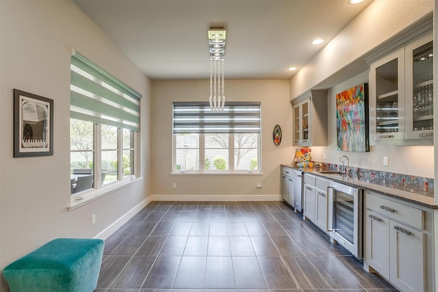 kitchen with baseboards, recessed lighting, glass insert cabinets, beverage cooler, and a sink