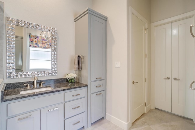 bathroom with a closet, vanity, and baseboards