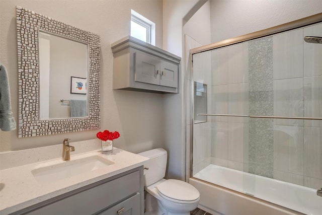 full bathroom featuring toilet, shower / bath combination with glass door, and vanity