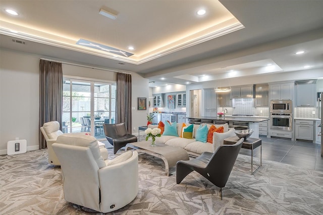 living area featuring recessed lighting, visible vents, and a tray ceiling