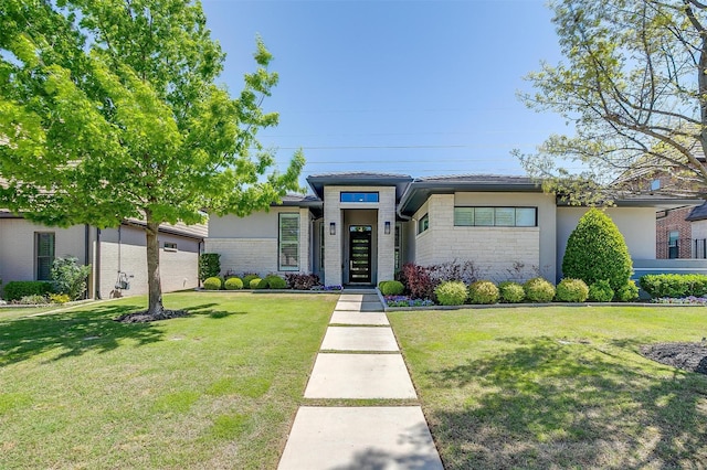 prairie-style home with a front yard, brick siding, and stucco siding
