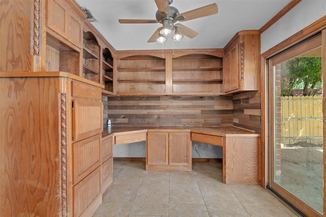 unfurnished office featuring a ceiling fan, built in desk, and light tile patterned floors