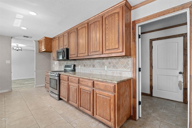 kitchen featuring backsplash, visible vents, brown cabinets, and stainless steel appliances