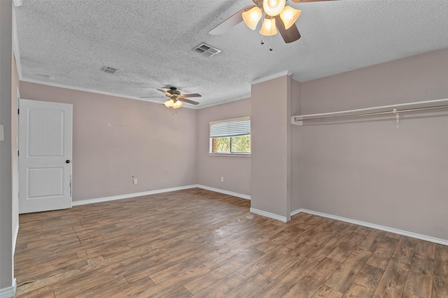 unfurnished bedroom featuring a textured ceiling, wood finished floors, visible vents, and baseboards