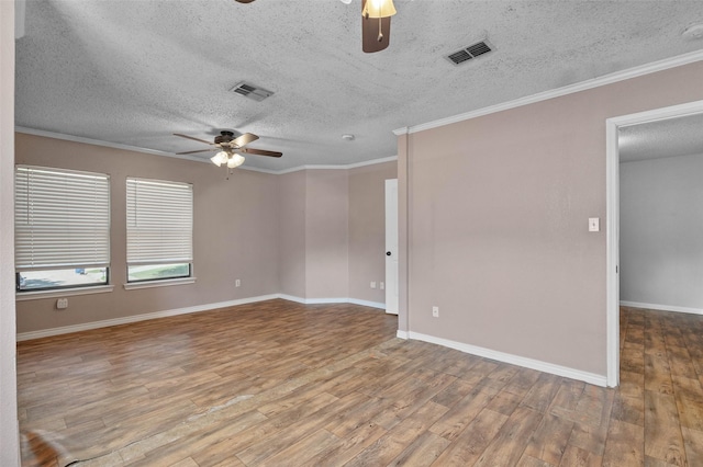 spare room with wood finished floors, visible vents, and ceiling fan