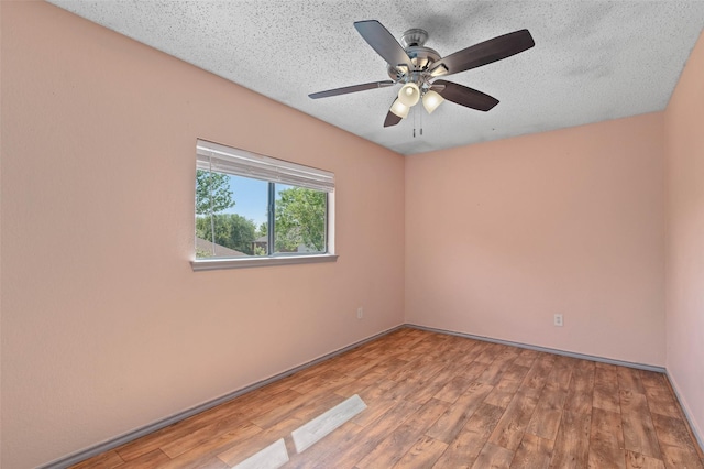 unfurnished room featuring ceiling fan, baseboards, wood finished floors, and a textured ceiling