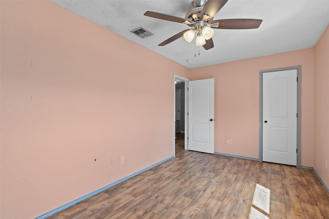 unfurnished bedroom with wood finished floors, visible vents, a ceiling fan, and baseboards