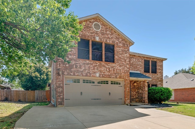 traditional-style home with an attached garage, driveway, brick siding, and fence