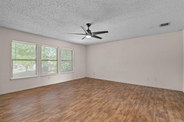 spare room featuring a wealth of natural light, a ceiling fan, wood finished floors, and visible vents