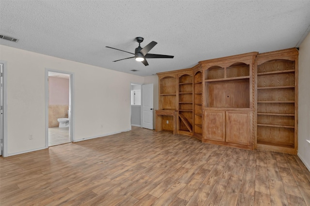 unfurnished living room featuring a textured ceiling, ceiling fan, light wood finished floors, baseboards, and visible vents