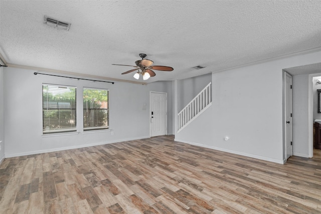 empty room featuring ceiling fan, wood finished floors, a textured ceiling, and visible vents