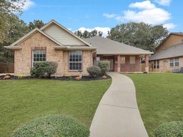 single story home featuring a front yard, roof with shingles, cooling unit, and stone siding