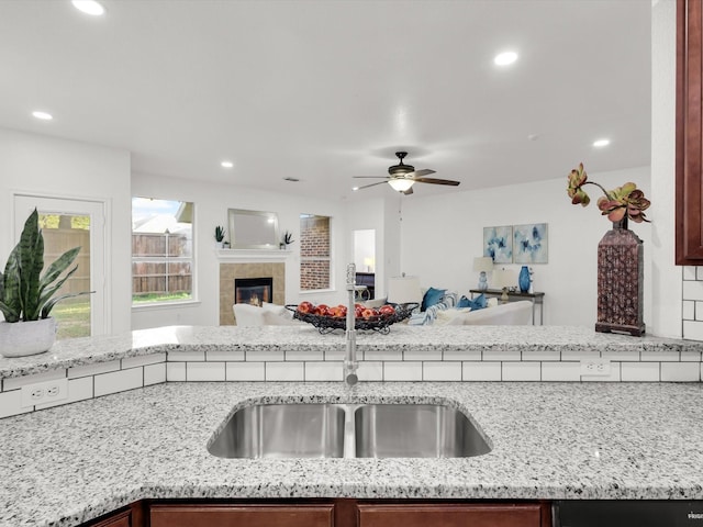 kitchen featuring a sink, open floor plan, recessed lighting, and light stone countertops