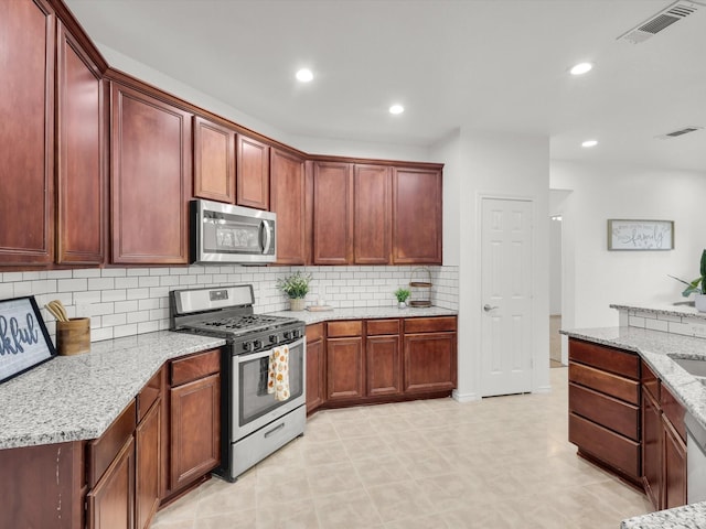 kitchen with light stone countertops, visible vents, recessed lighting, stainless steel appliances, and decorative backsplash