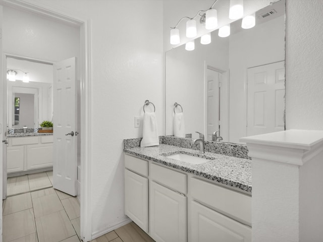full bath featuring two vanities, a sink, and visible vents