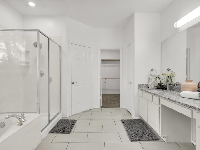 full bath with a spacious closet, a shower stall, vanity, tile patterned flooring, and a garden tub