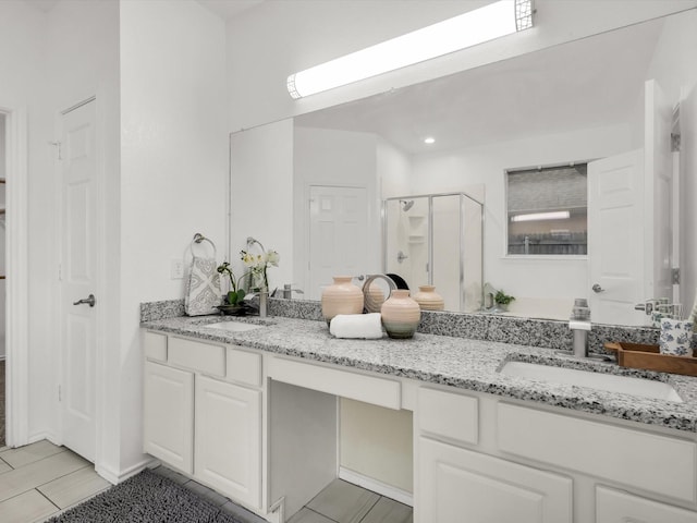 bathroom featuring tile patterned floors, double vanity, a sink, and a stall shower